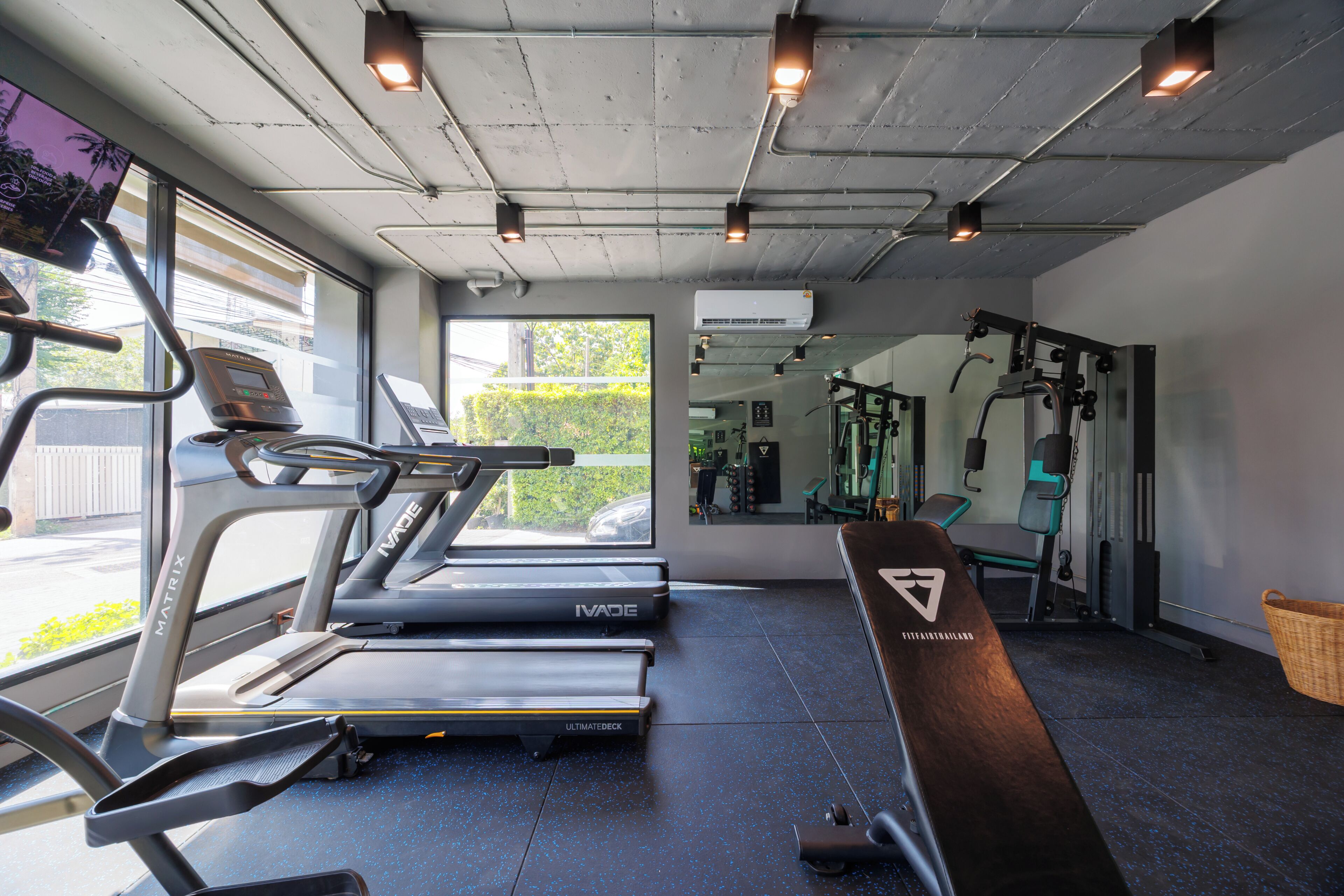 A gym with treadmills, a bench, and a mirror.