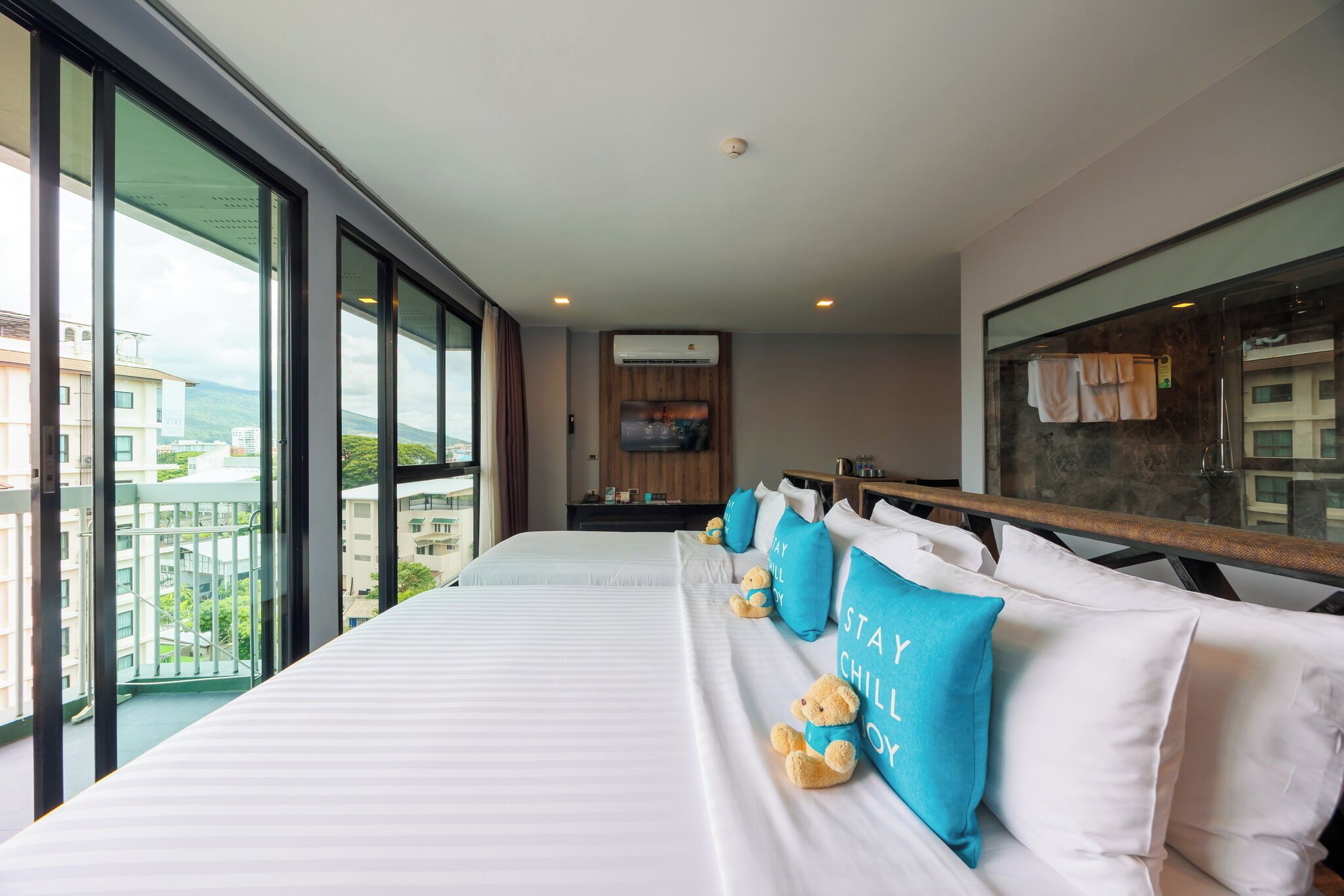 A hotel room with a large bed, a balcony with a view, a TV, and a minibar.