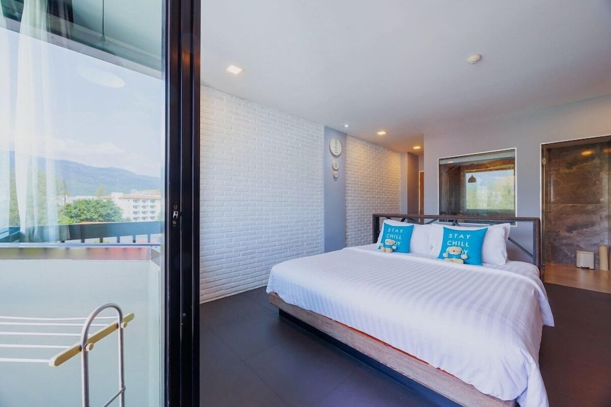 A bedroom with a bed, a window, and a view of the outside.