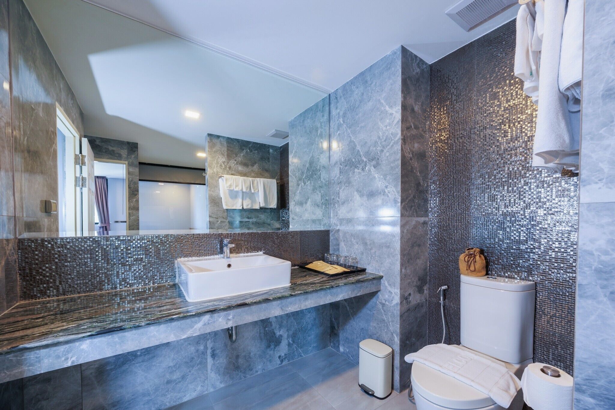 Une salle de bain moderne avec un grand miroir, un lavabo blanc et des toilettes.