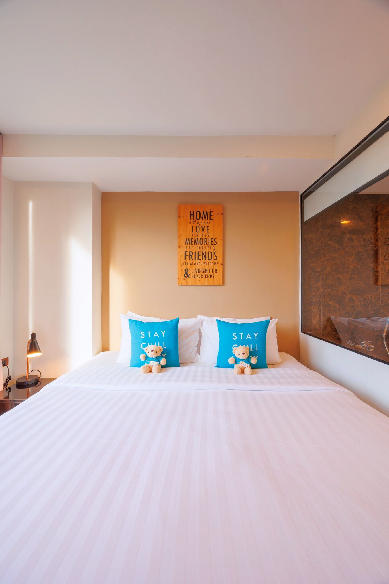 Una habitación de hotel con una cama grande, dos almohadas con un diseño de oso, un letrero en la pared y una mesita de noche con una lámpara.