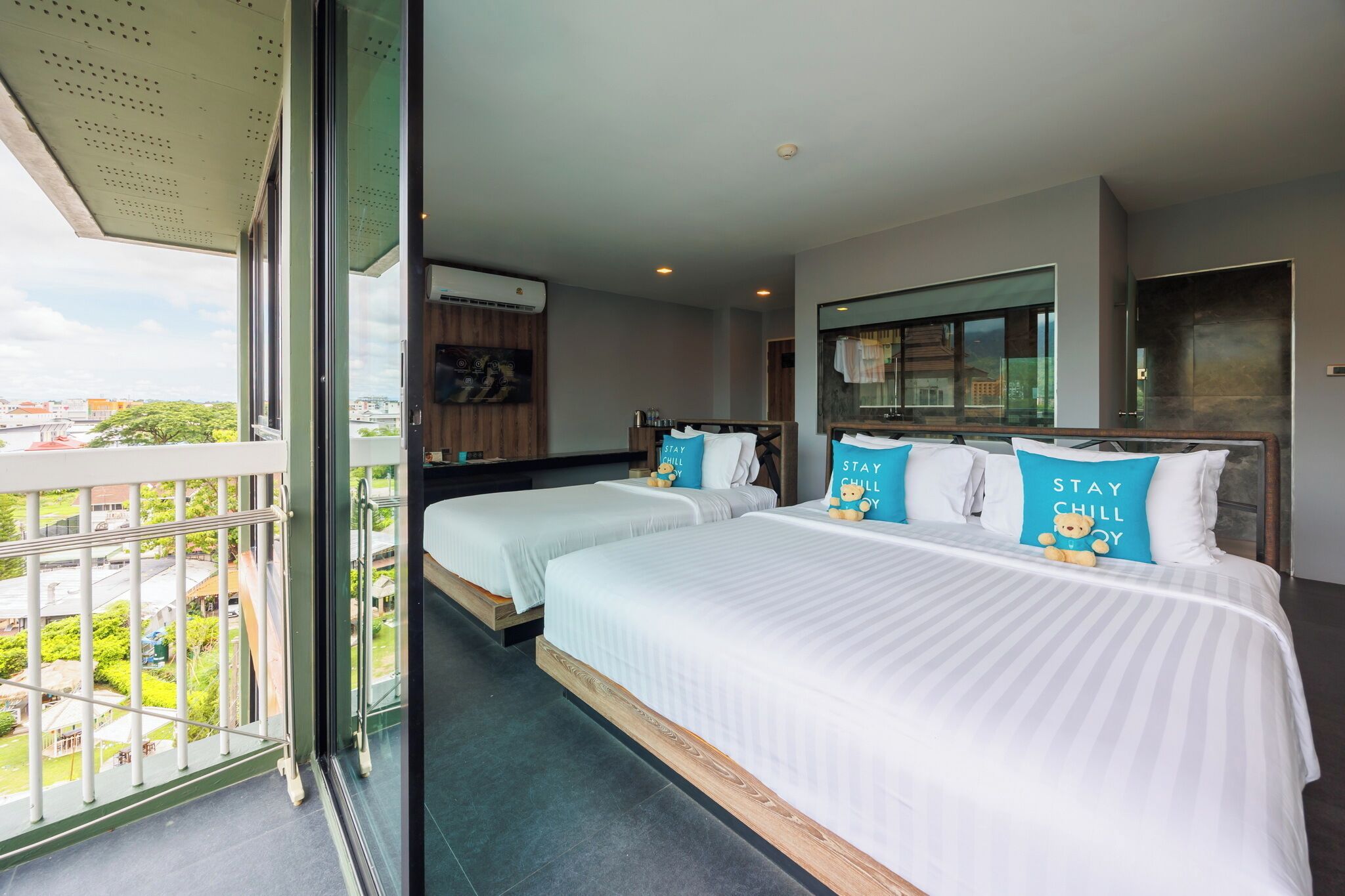 A hotel room with two beds, a balcony, and a city view.
