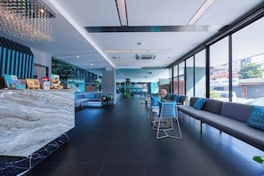 En moderne lobby med en marmorindskrivning, siddeområder og store vinduer med udsigt til gaden.