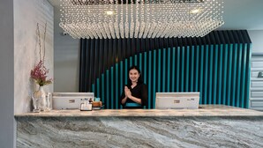 A reception desk with two laptops, a vase with branches, and a decorative chandelier. - Cross Vibe Chiang Mai Decem (Chiang Mai)