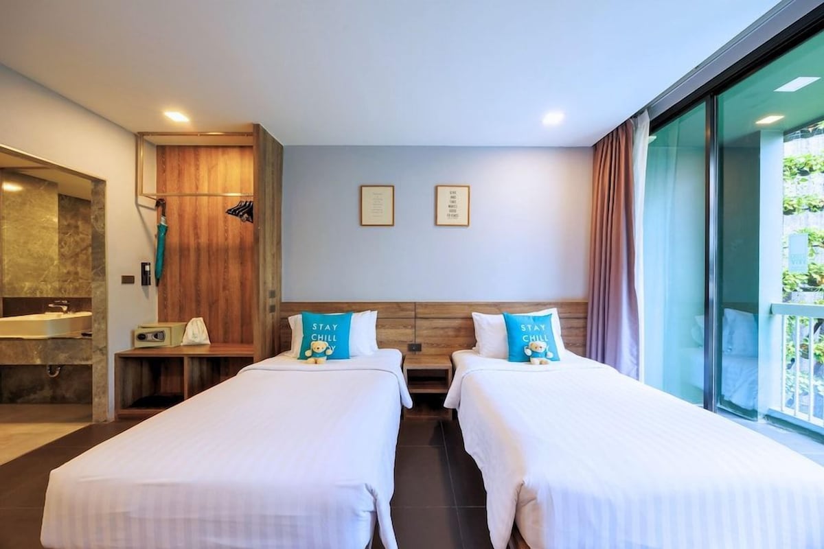 Habitación de hotel con dos camas, baño y vistas a zonas verdes.
