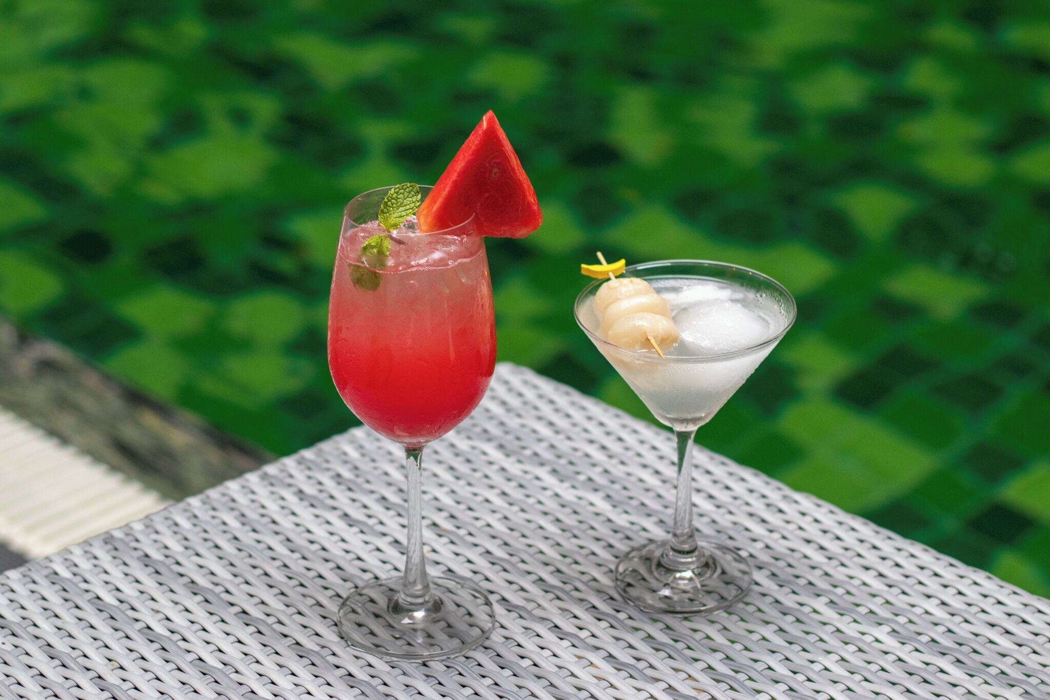 Two drinks on a table with a green background.