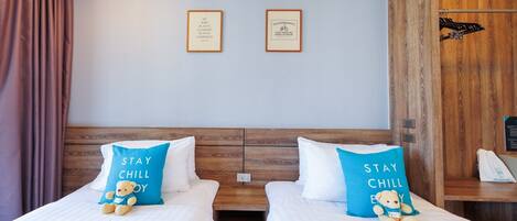 A hotel room with two beds, each with a pillow that says 'STAY CHILL'. There are two framed quotes on the wall above the beds.