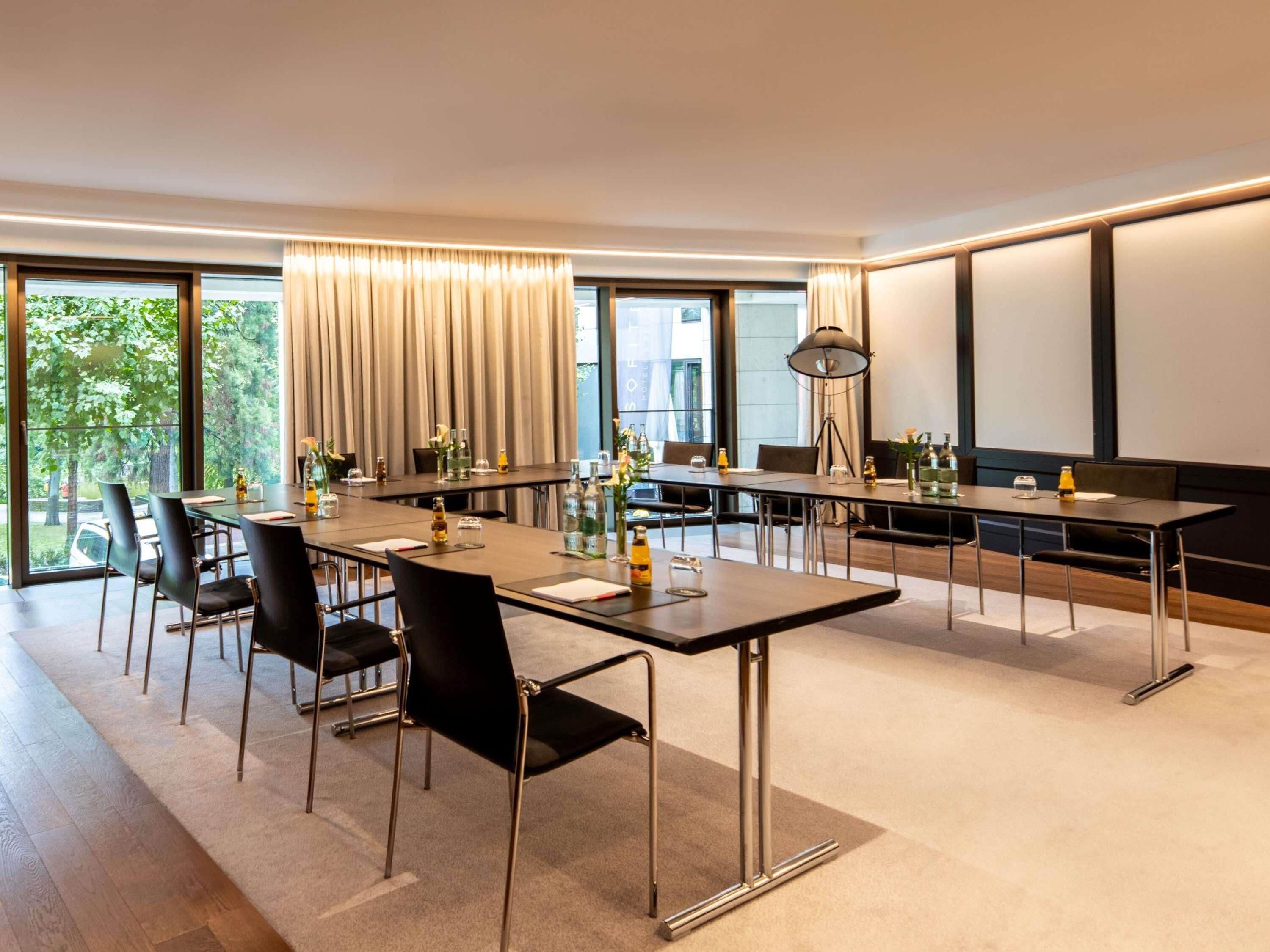 A modern conference room with a long table, chairs, and a projector screen.