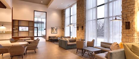Un vestíbulo amplio con diversas opciones de asientos, ventanas grandes y una pared de acento de piedra.