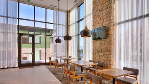 A spacious dining area with large windows, a brick wall, and modern pendant lights. - Hyatt Place Park City (Park City)