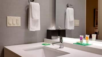 A bathroom with a white sink, a mirror, and two towels hanging on hooks.