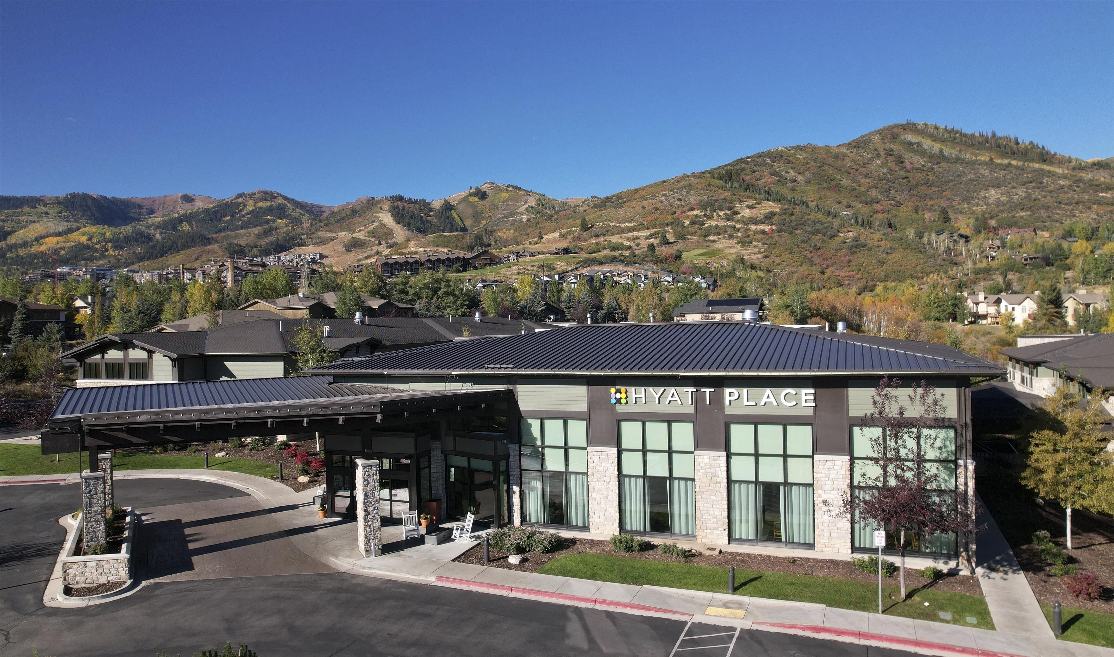 A modern building labeled "HYATT PLACE" with a covered parking area, surrounded by a mountainous landscape.