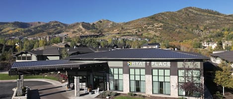 Moderni rakennus, jonka kyltissä lukee ”HYATT PLACE”, ja jossa on katettu pysäköintialue. Rakennuksen ympärillä on vuoristomaisema.
