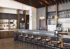 Una cocina moderna con barra, que incluye una encimera larga, taburetes de bar y lámparas colgantes.