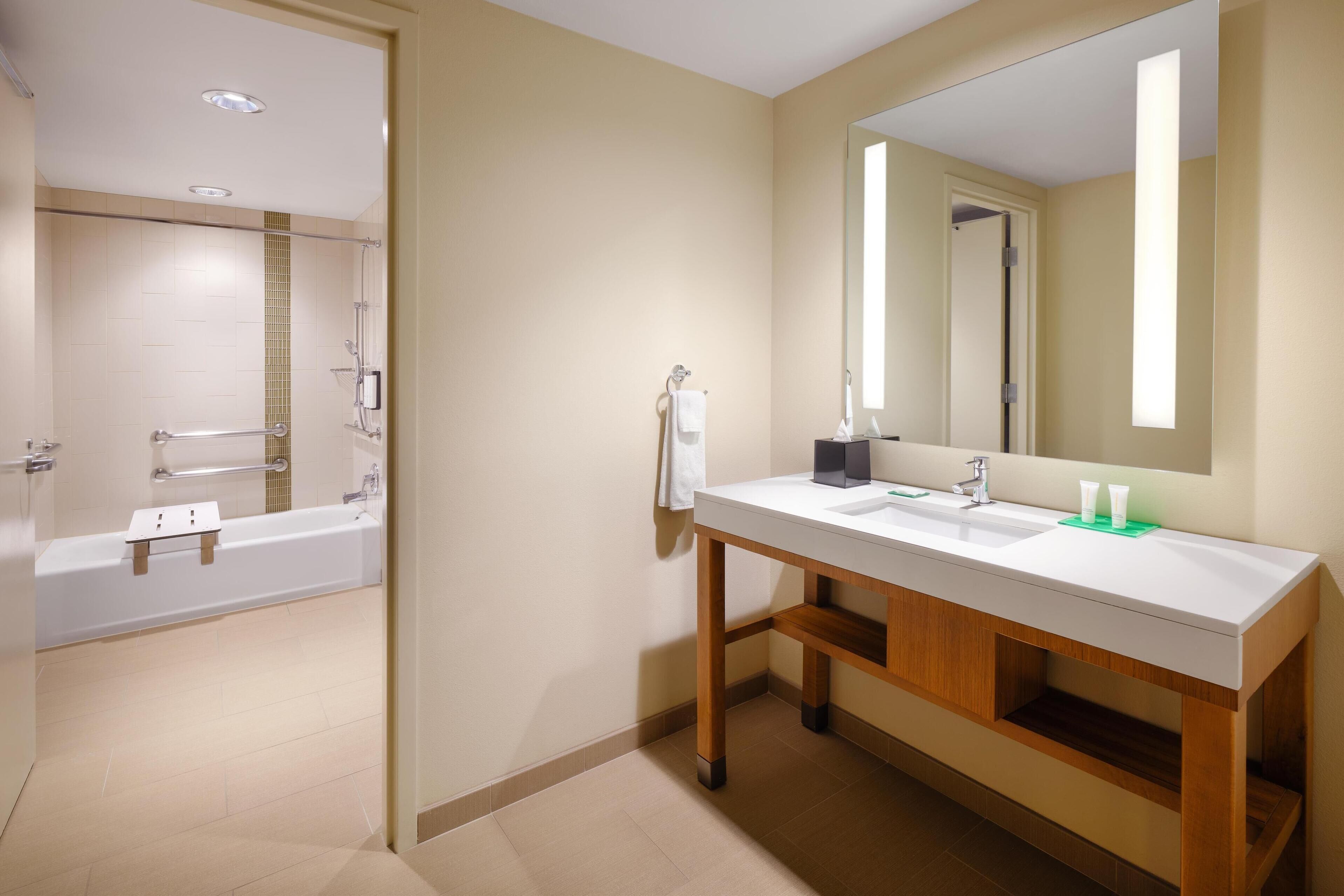 A modern bathroom with a bathtub, a sink with a mirror, and a towel rack.