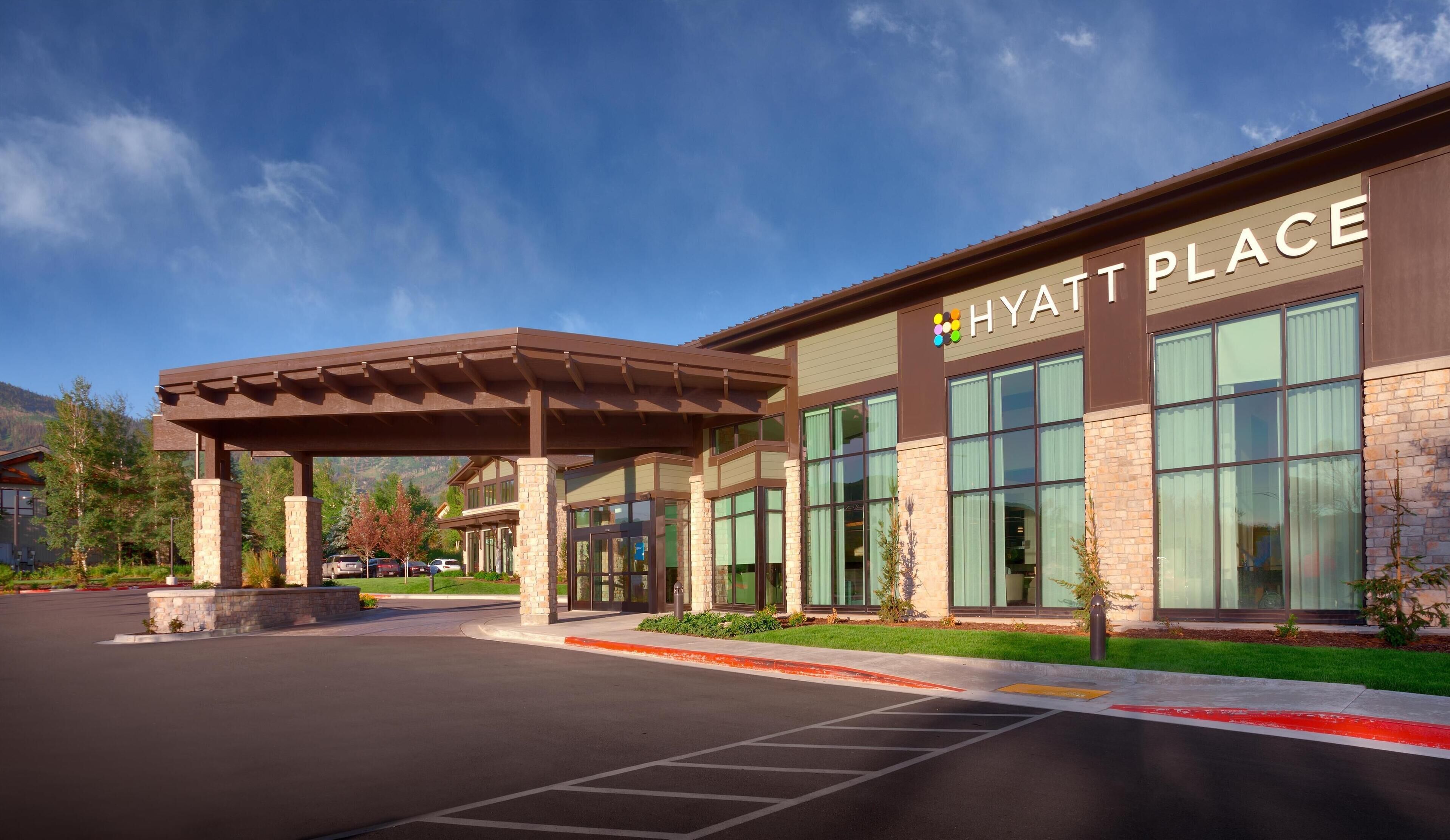 Een Hyatt Place hotel met een overdekte ingang, grote ramen en een gevel van natuursteen.