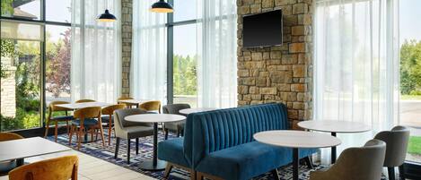 A modern indoor seating area with a stone wall, large windows, and a blue sofa.