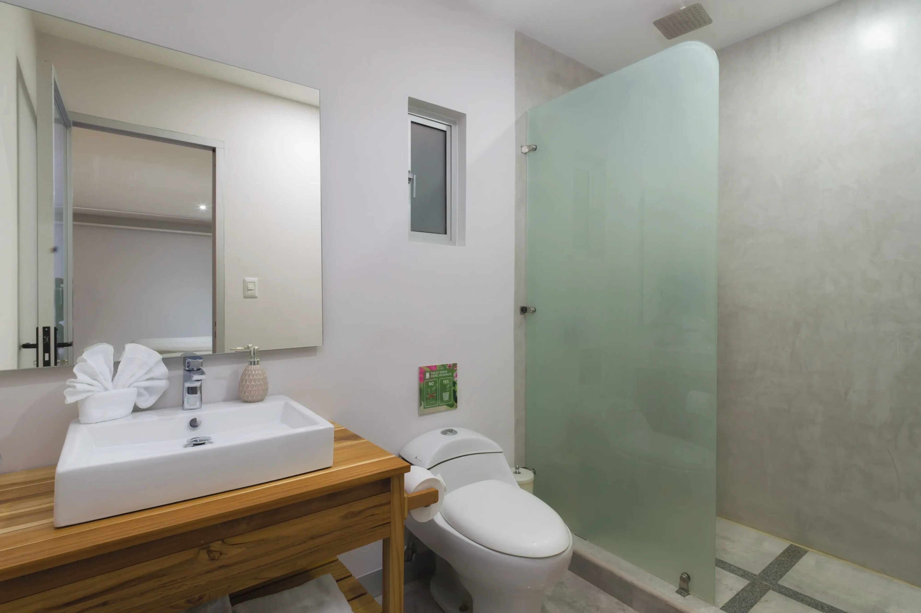 A bathroom with a white sink, mirror, and toilet.