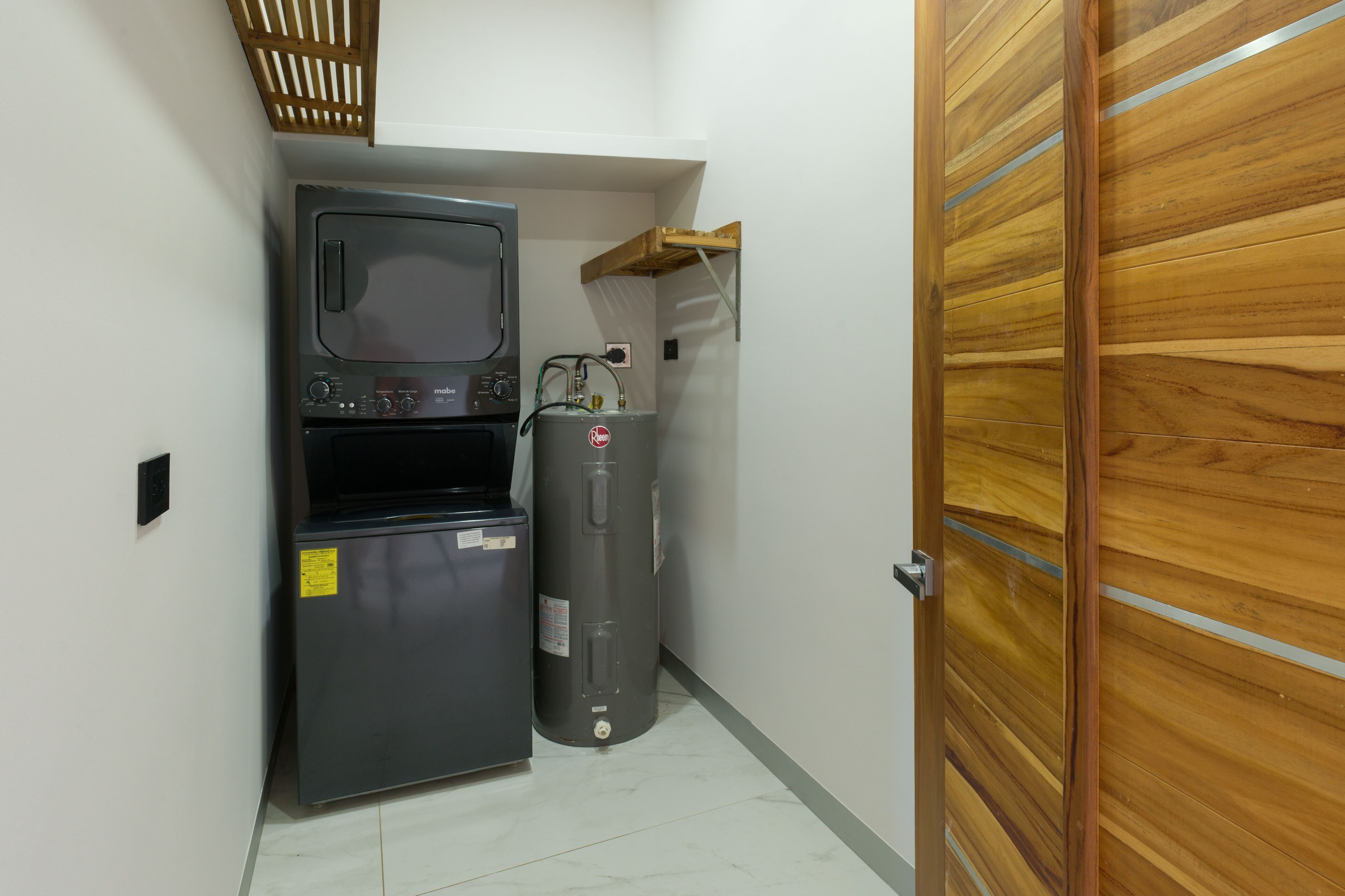 Un lavadero funcional y compacto con calentador de agua, microondas y un refrigerador pequeño.