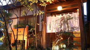 A traditional Japanese building with a wooden exterior, a covered entrance, and signage in Japanese. - Oyado Ikegami (Uozu)