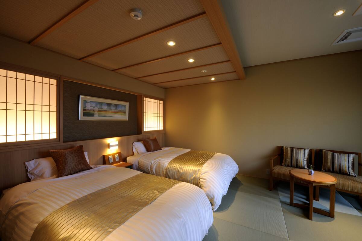 A hotel room with two beds, a sofa, a small table, and a picture on the wall.