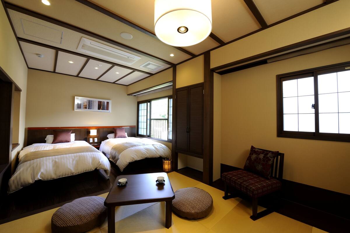 A traditional Japanese-style room with two beds, a small table, and a bench.