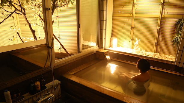 A traditional Japanese onsen with a wooden bathtub, a bamboo screen, and a small statue of a rabbit. - Oyado Ikegami (Uozu)