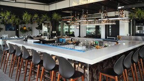 A modern bar area with a long counter, multiple stools, and hanging glassware. - Renaissance Montreal Downtown Hotel (Montreal)