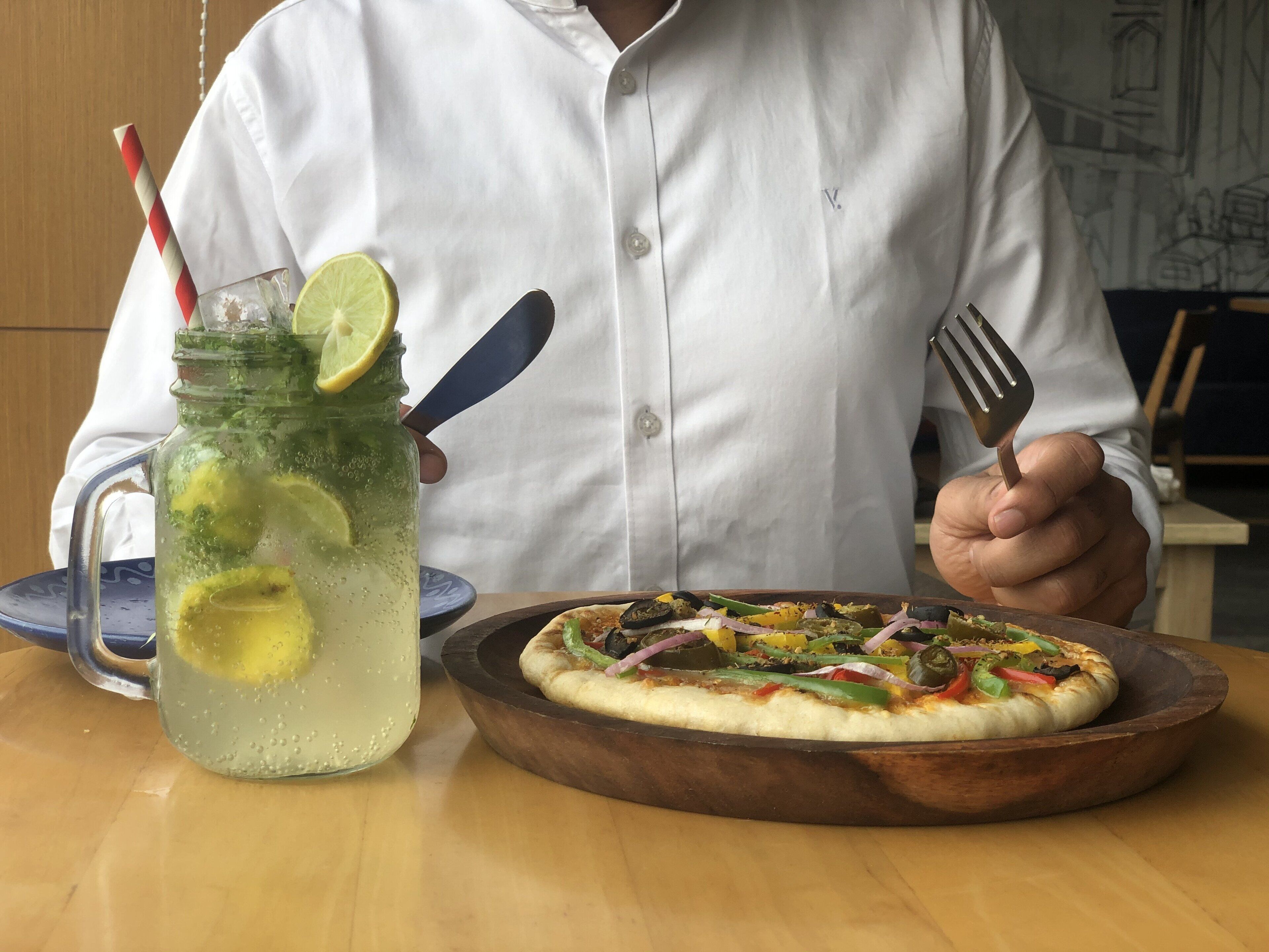 Una persona sentada a una mesa con comida y bebida.