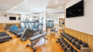 Une salle de sport équipée de tapis de course, de vélos elliptiques et de poids libres.