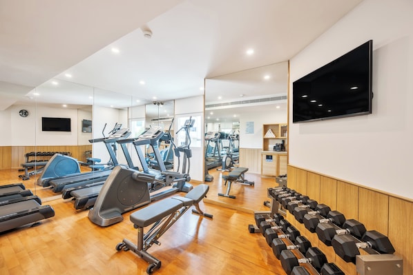 Een sportschool met loopbanden, elliptische trainers en losse gewichten.