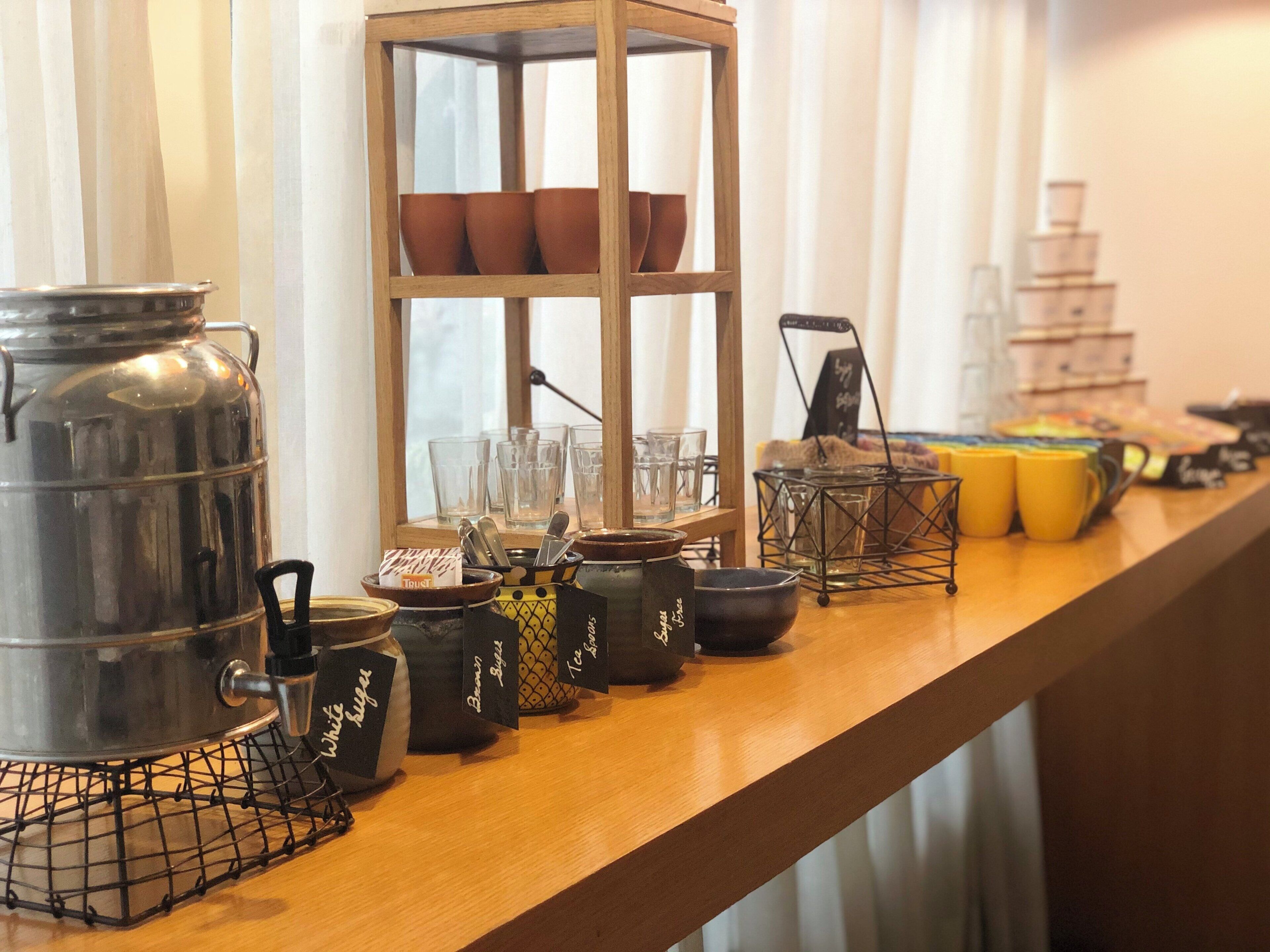 A bar area with various containers, glasses, and a tiered display of mugs.