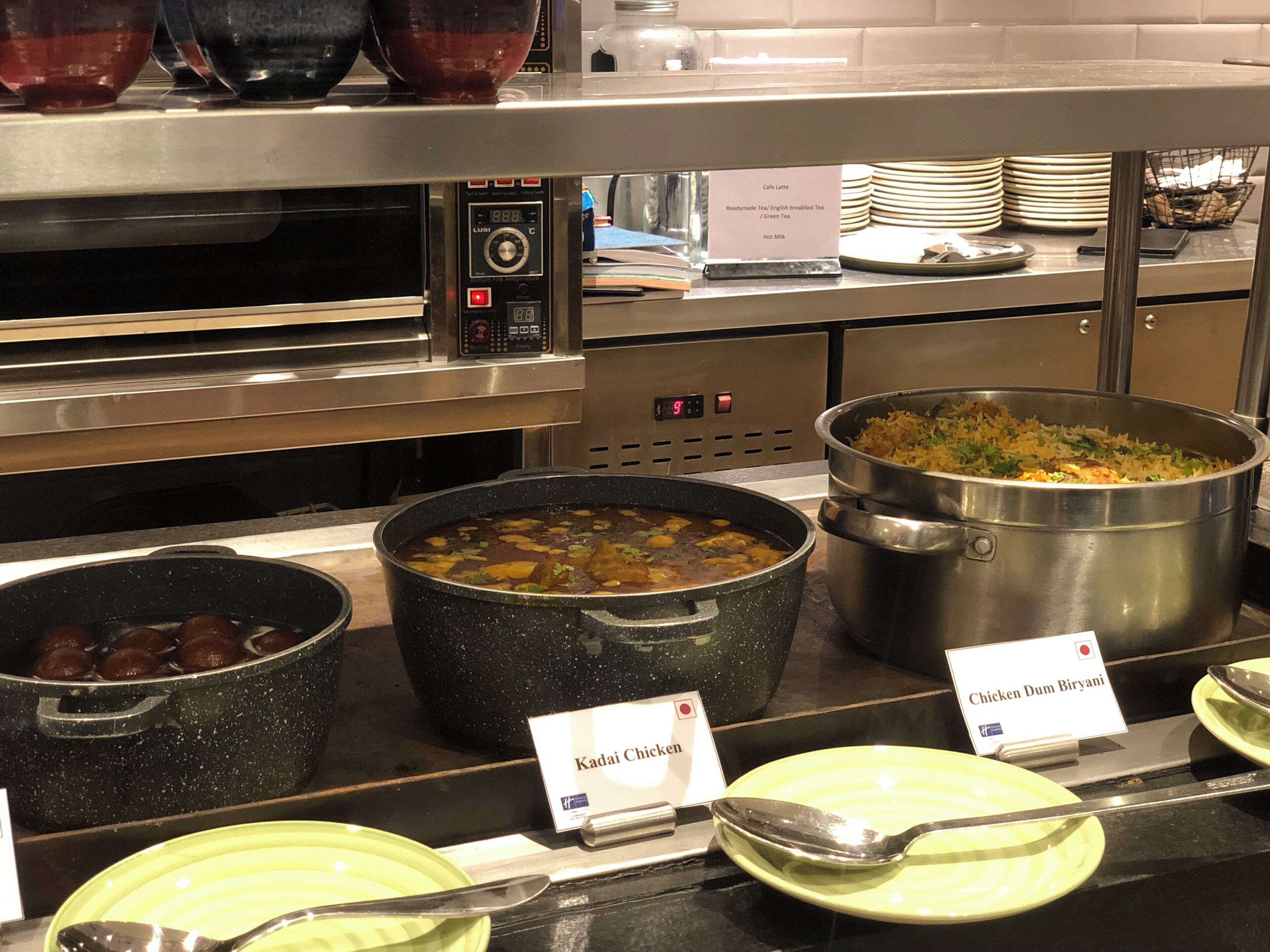 Ein Buffet mit verschiedenen Gerichten, darunter Hühnchen Dum Biryani, Kadai-Hühnchen und Reis.