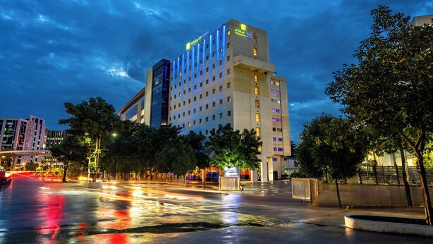 Un hôtel à étages, avec une enseigne bien visible au sommet et un parking bordé d’arbres.