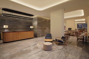 A modern lobby with a reception desk, seating area, and a bar.