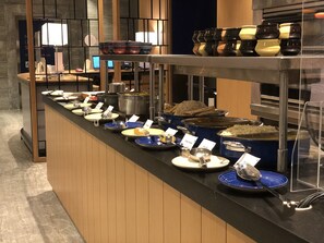 Disposición de buffet con diversos alimentos y utensilios para servir.