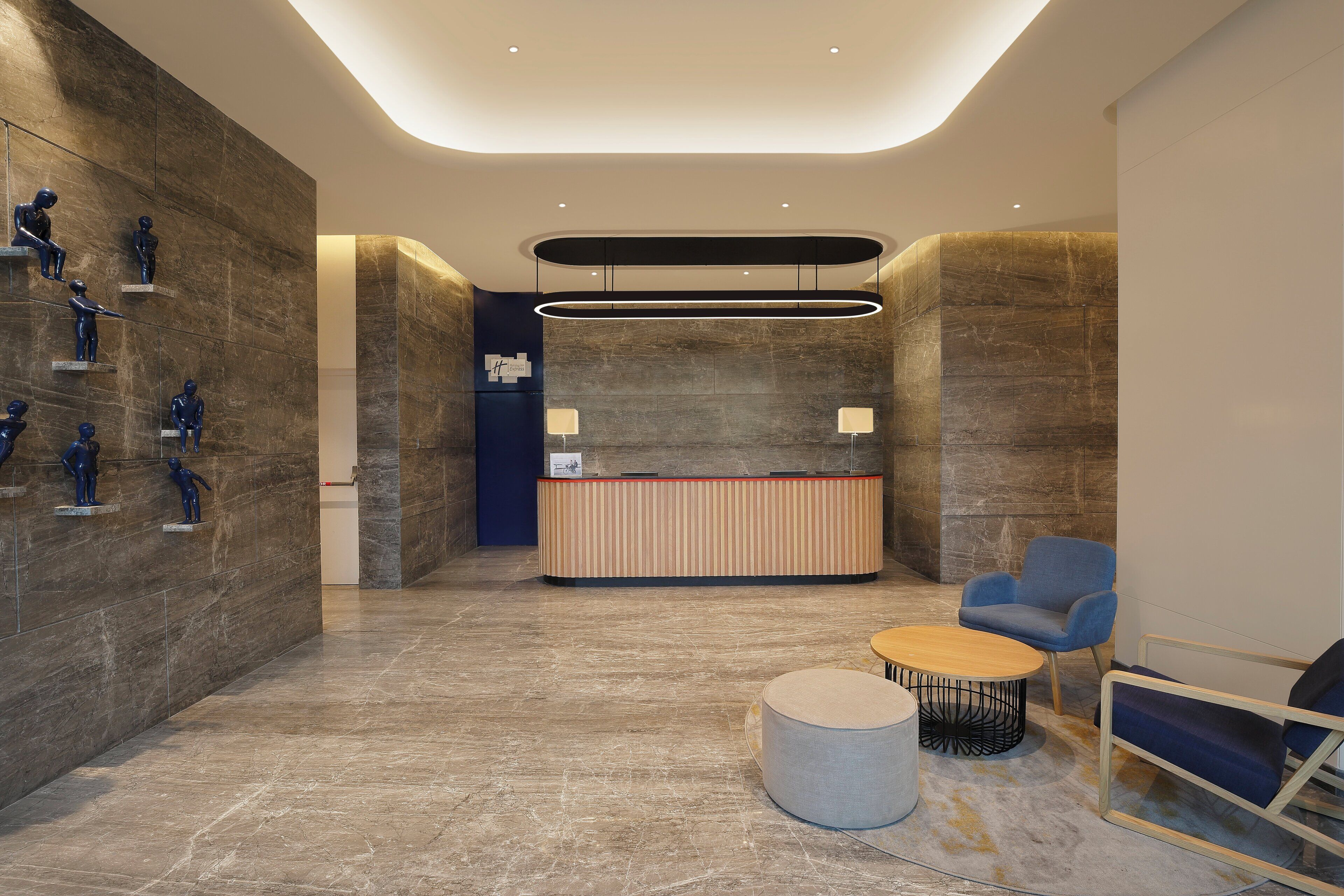 A modern reception area with a marble floor, a reception desk, a blue armchair, and a round coffee table.