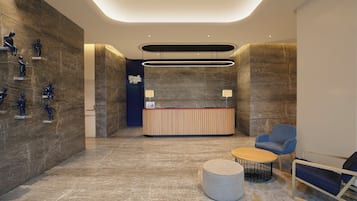 A modern reception area with a marble floor, a reception desk, a blue armchair, and a round coffee table.