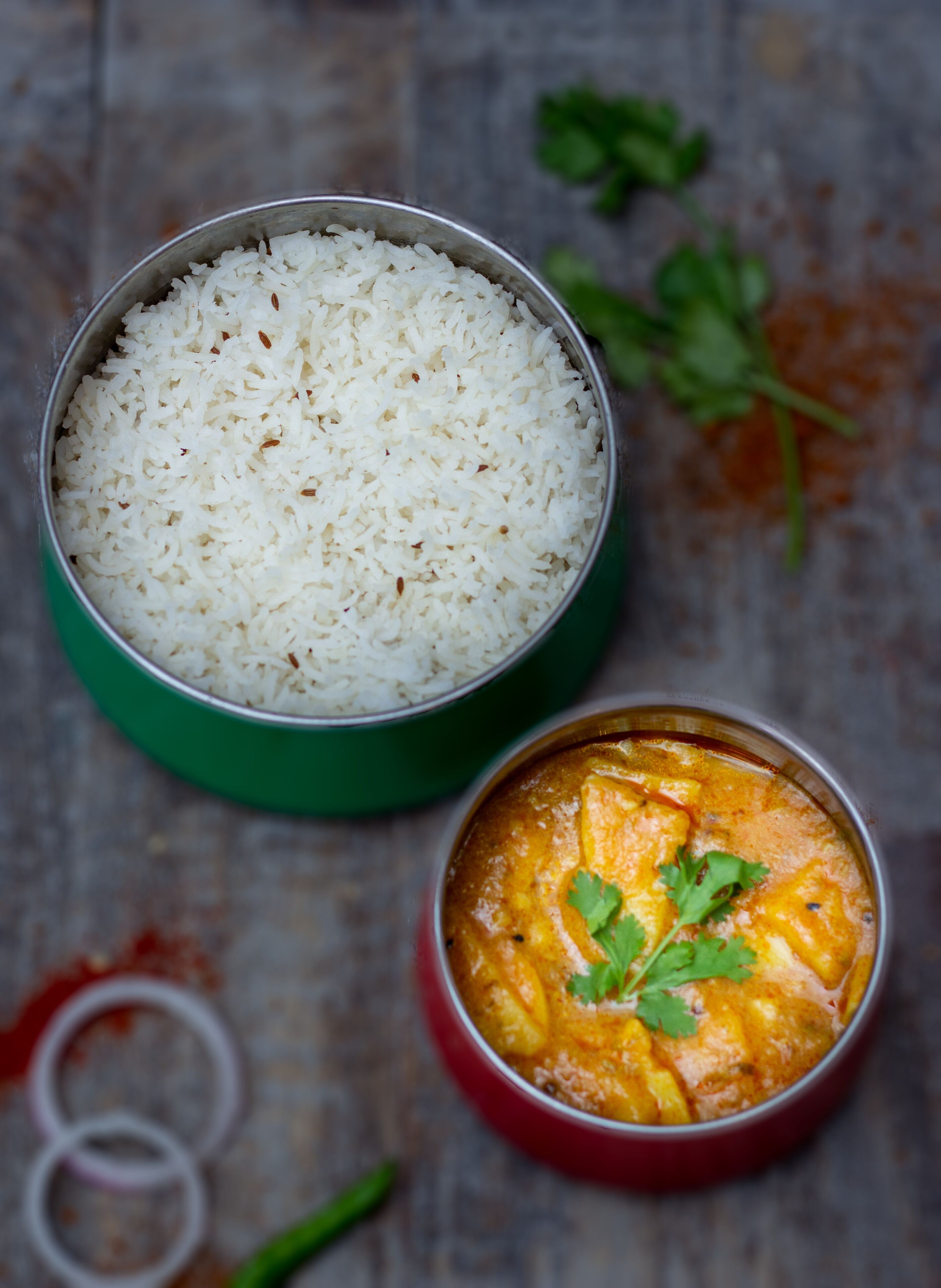 Un bol de riz blanc et un bol de curry, le tout garni.