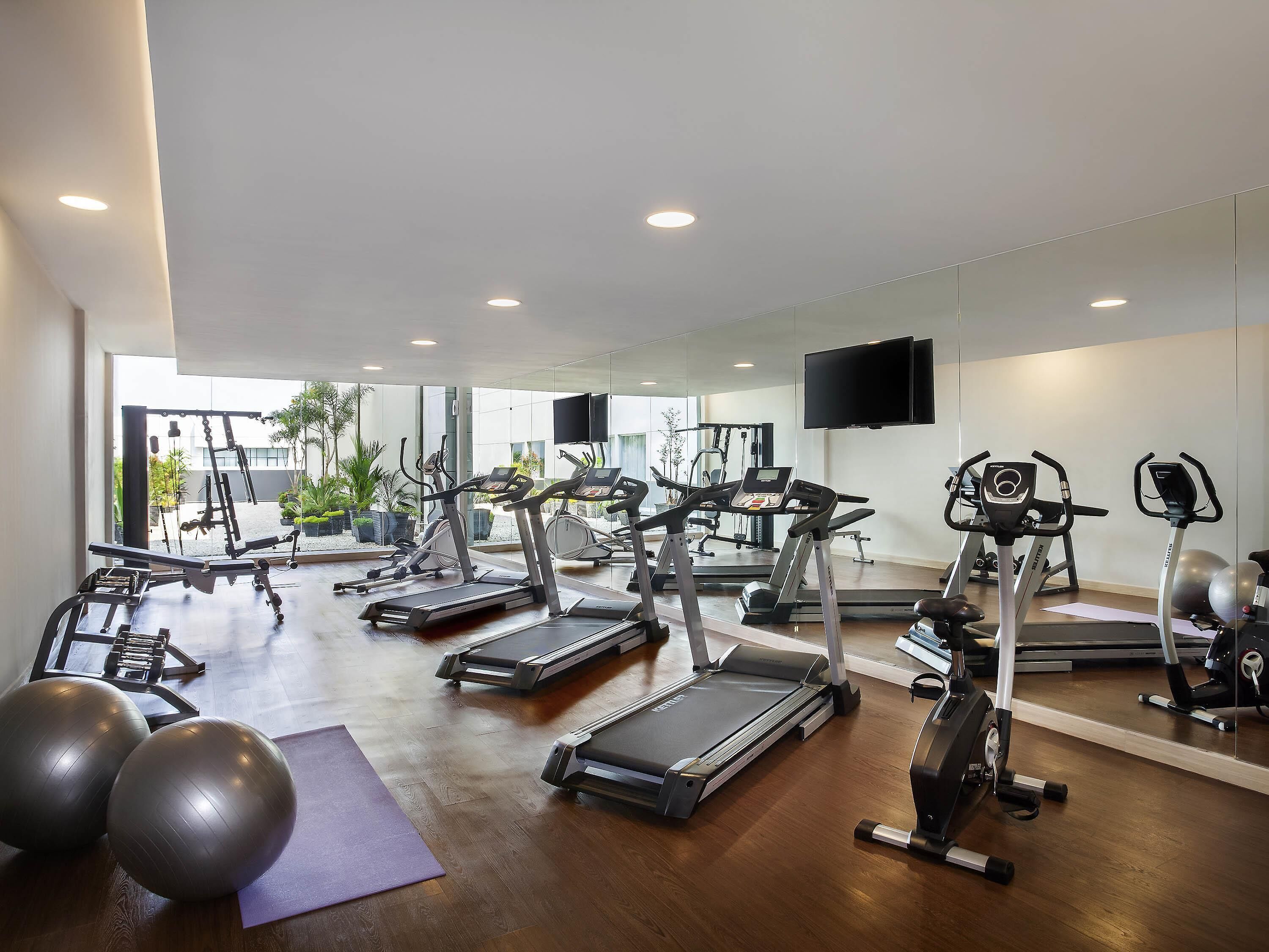 A gym with treadmills, exercise balls, and a mirror.