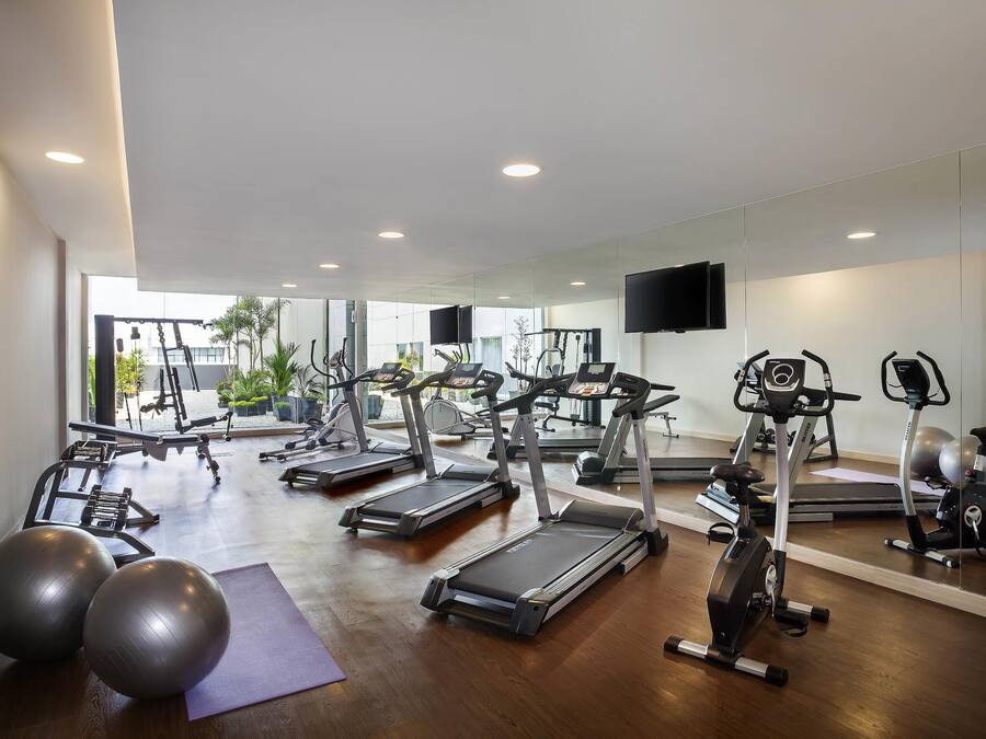 A gym with treadmills, exercise balls, and a mirror.