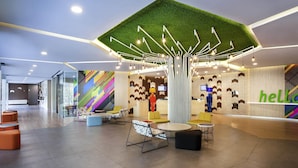 A modern lobby with a green artificial grass ceiling, colorful geometric wall patterns, and a 'hello' sign. - Ibis Styles Jakarta Sunter (Jakarta)