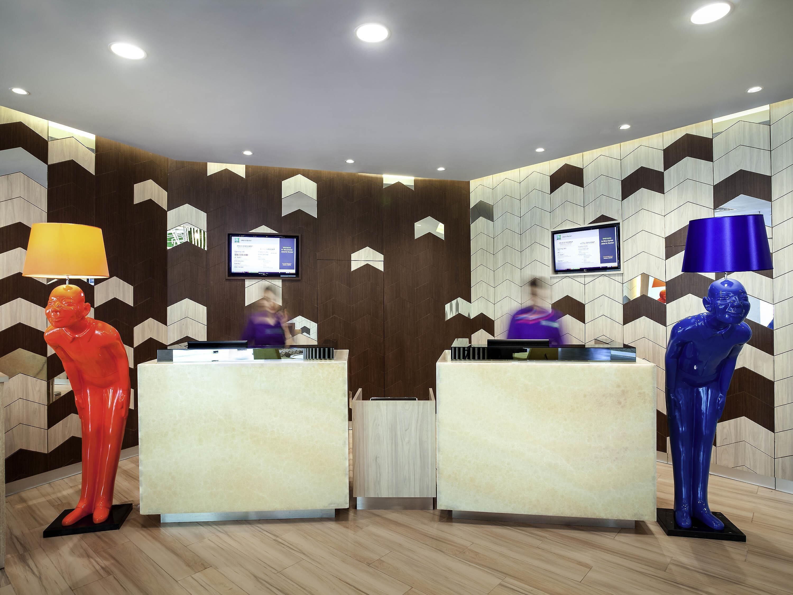 Un área de recepción con dos mostradores, una pantalla digital y un diseño de pared geométrico moderno.