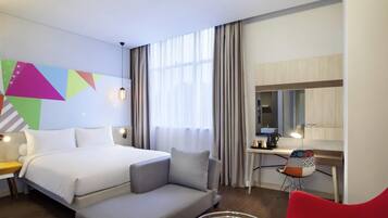 Una habitación de hotel con una cama, un escritorio, una silla y una mesita.