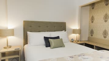A hotel room with a bed, two bedside tables, lamps, and a decorative wall panel.