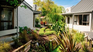Una propiedad residencial con jardín, cerca de madera y un pequeño estanque.