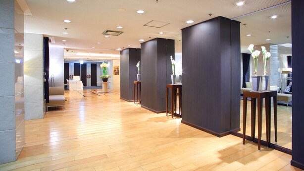 A spacious hallway with wooden flooring, dark walls, and multiple light fixtures.