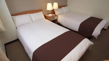 Two adjacent beds with white linens and brown throw blankets, each with a bedside table featuring a lamp and a clock.