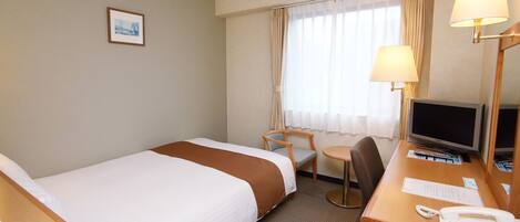 A hotel room with two beds, a desk with a computer, a telephone, and a chair.