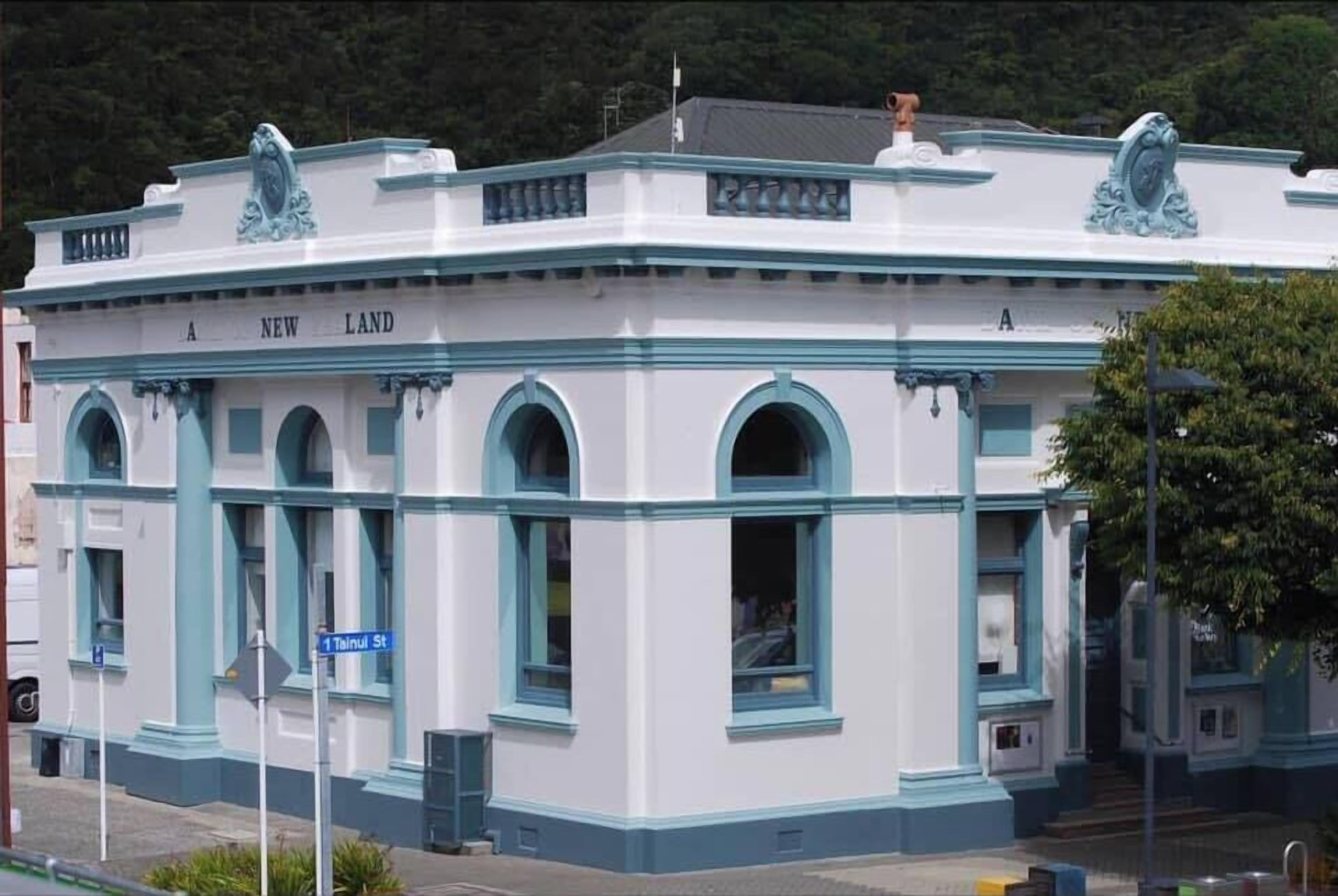 A white building with blue trim and arched windows, labeled "A NEW LAND."